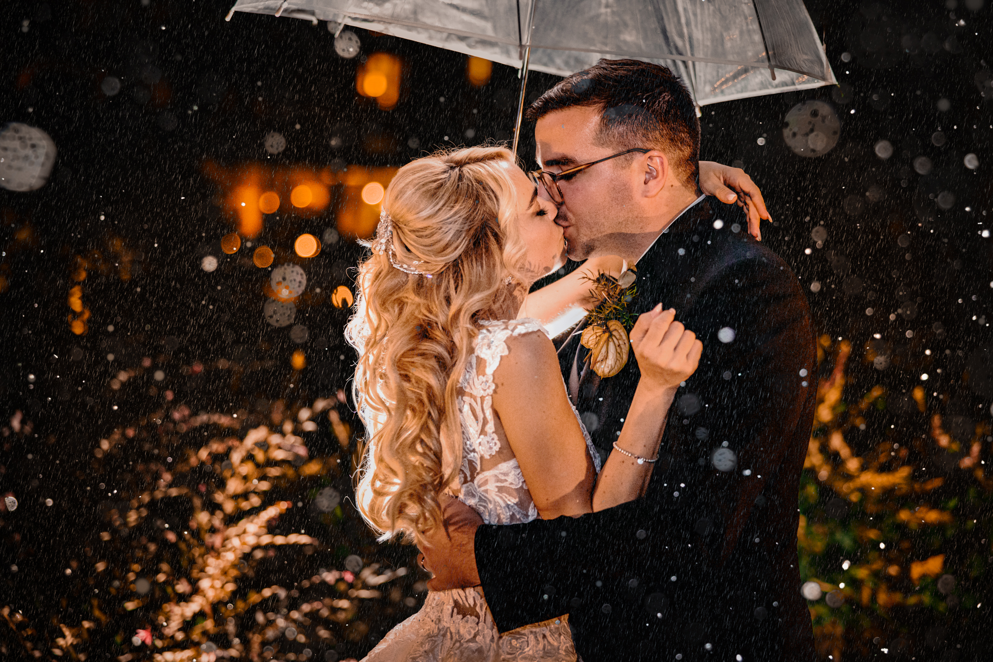Sposi che si baciano sotto l'ombrello